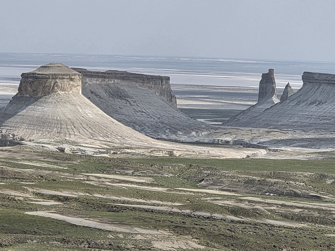 The view from Bozzhyra's upper plateau-rim viewpoint, looking down over the chalk outliers to the salt flat beyond