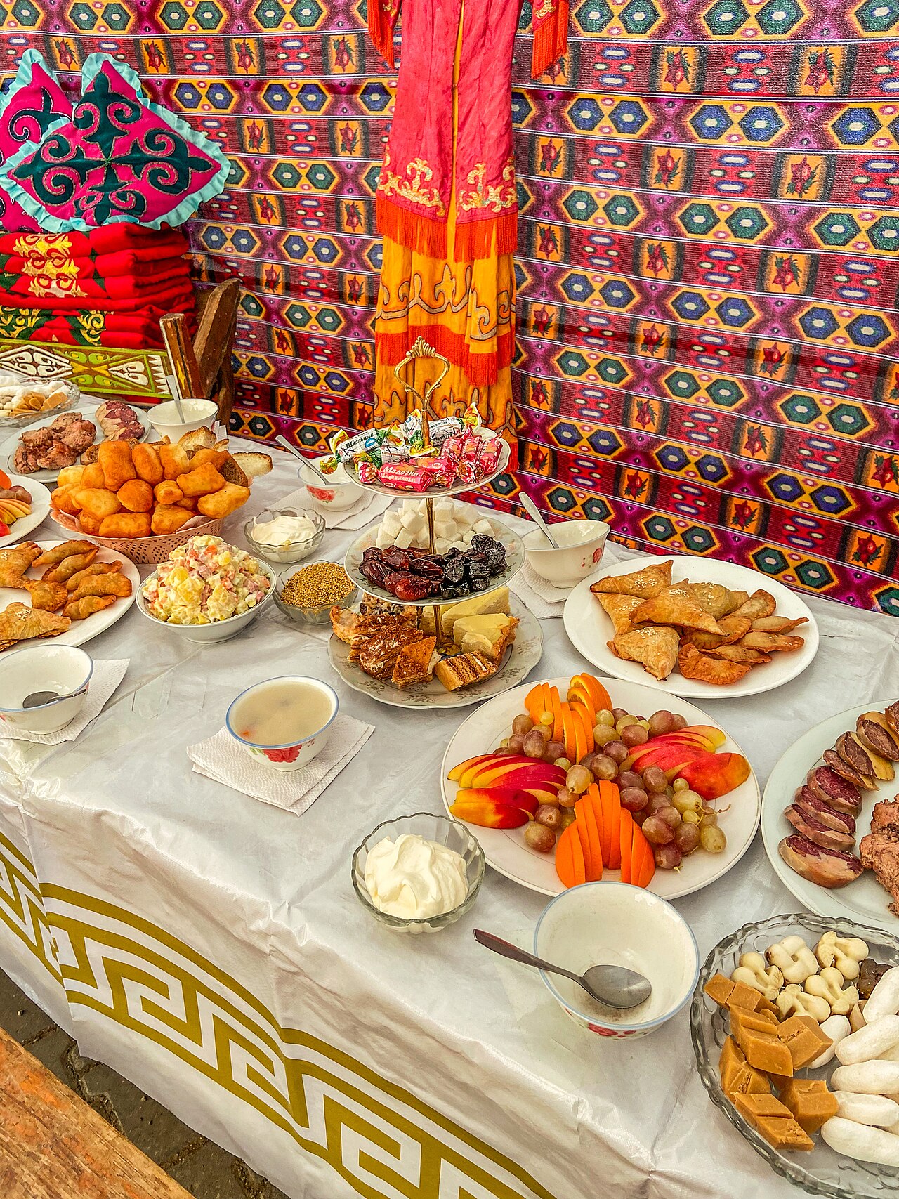 A dastarkhan laid inside a yurt with baursak, samsa, kazy, kurt, dried fruit and sweets