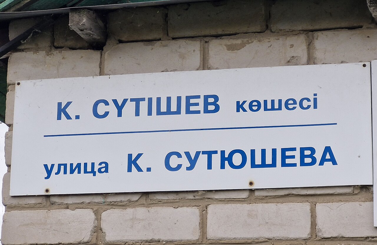 A street nameplate in northern Kazakhstan with the Kazakh name above and the Russian below