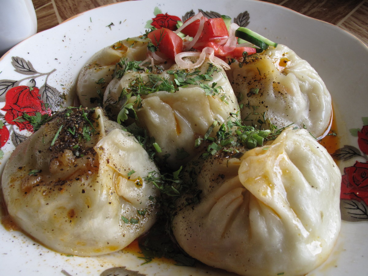 A plate of steamed manti dumplings with herbs and pepper